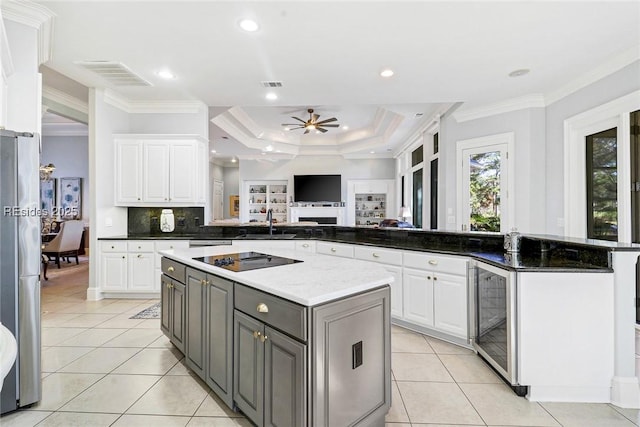 kitchen featuring wine cooler, a center island, black electric cooktop, a tray ceiling, and white cabinets