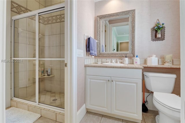 bathroom with tile patterned flooring, vanity, a shower with shower door, and toilet