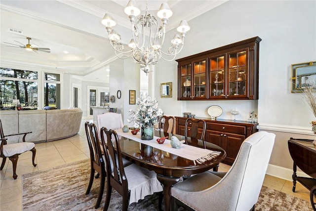 dining room with ornamental molding, a tray ceiling, ceiling fan with notable chandelier, and light tile patterned floors