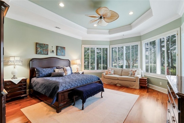 bedroom featuring crown molding, ceiling fan, a tray ceiling, and light hardwood / wood-style floors