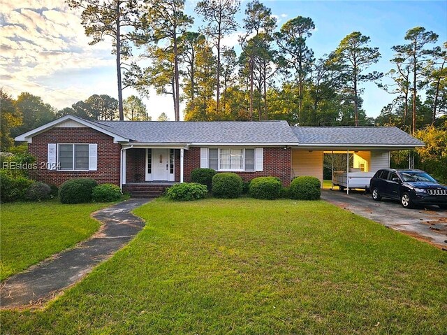 ranch-style home featuring a carport and a front lawn