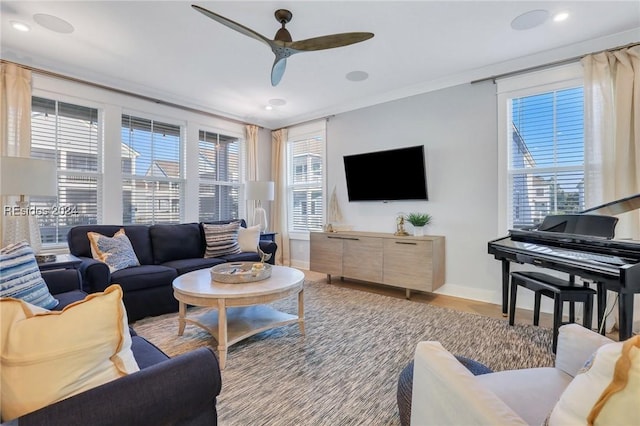 living room featuring crown molding, a healthy amount of sunlight, ceiling fan, and light hardwood / wood-style floors