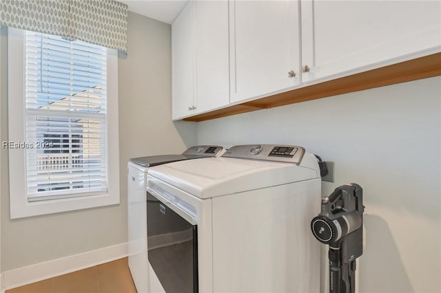 laundry area with tile patterned flooring, washing machine and dryer, and cabinets