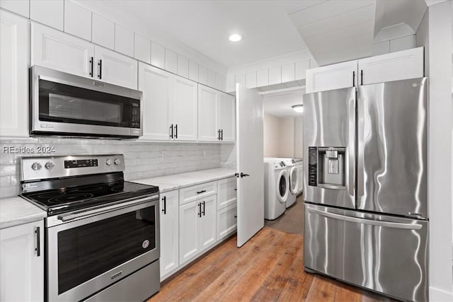 kitchen with appliances with stainless steel finishes, white cabinetry, tasteful backsplash, separate washer and dryer, and light wood-type flooring