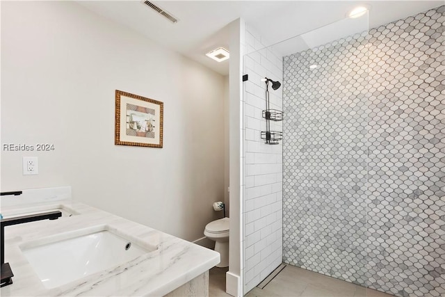 bathroom with vanity, a tile shower, and toilet