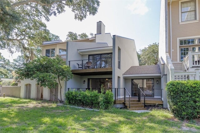 back of house featuring a balcony and a lawn