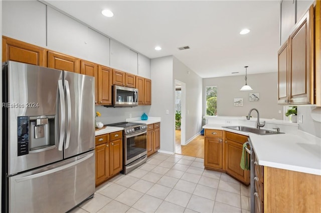 kitchen featuring appliances with stainless steel finishes, pendant lighting, sink, light tile patterned floors, and kitchen peninsula