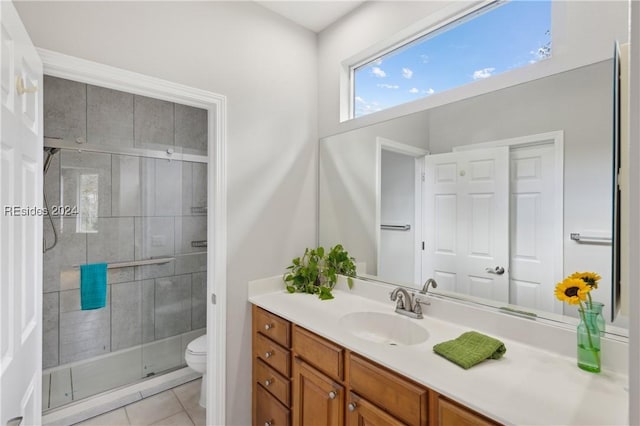 bathroom with vanity, a shower with shower door, tile patterned floors, and toilet