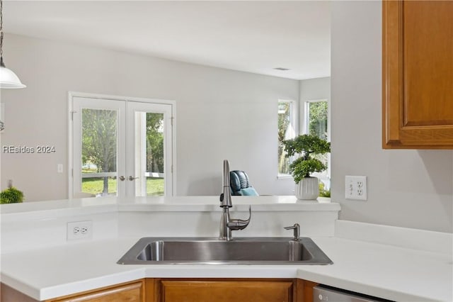 kitchen with decorative light fixtures, dishwasher, sink, and a wealth of natural light