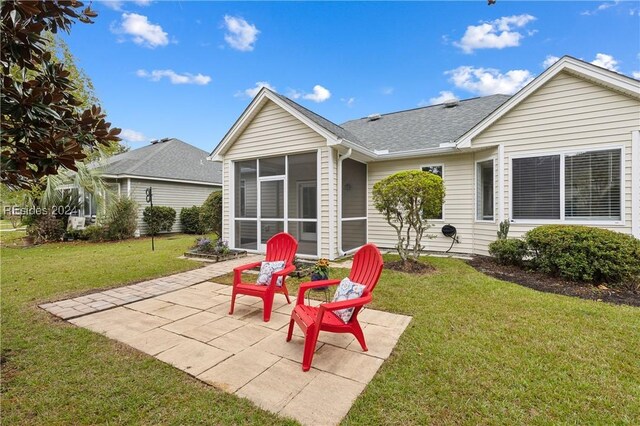 rear view of house with a sunroom, a yard, and a patio area