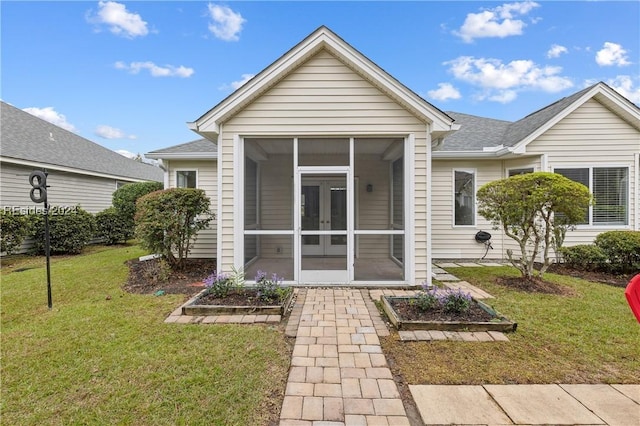 back of property featuring a lawn and a sunroom