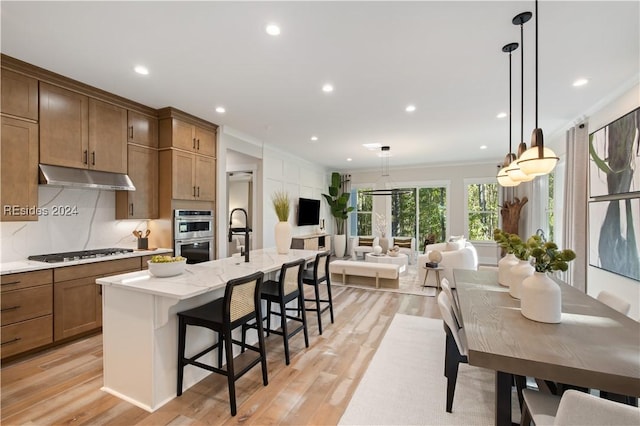 kitchen with pendant lighting, stainless steel appliances, a kitchen breakfast bar, and a center island with sink