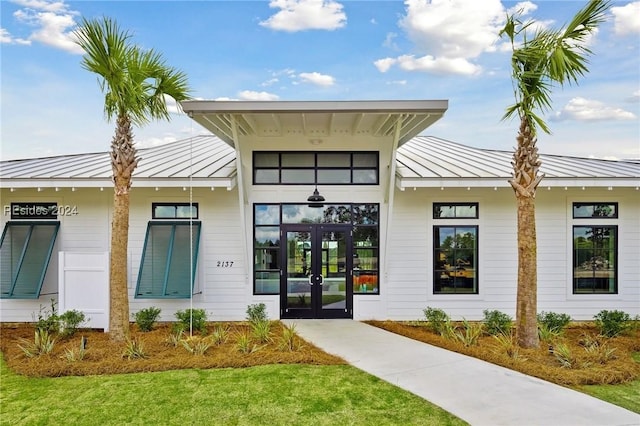 view of exterior entry with a yard and french doors