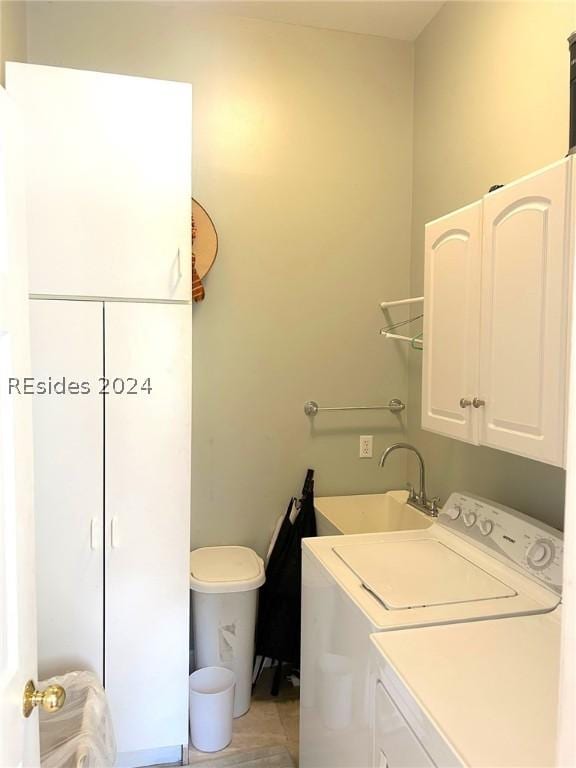 washroom with cabinets, washer and dryer, and sink