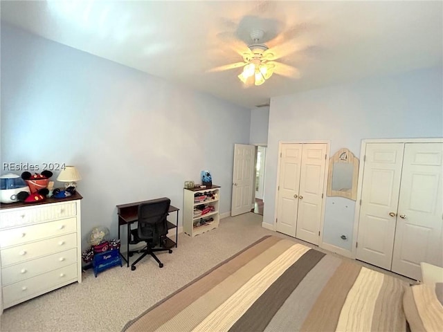 carpeted bedroom with ceiling fan and two closets