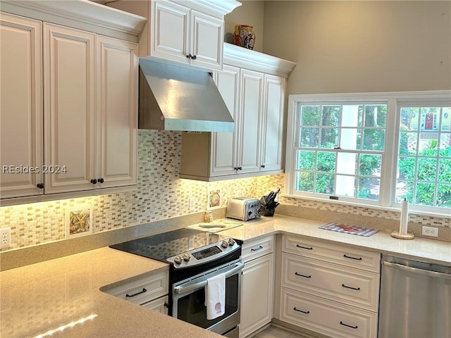 kitchen with extractor fan, appliances with stainless steel finishes, and white cabinets