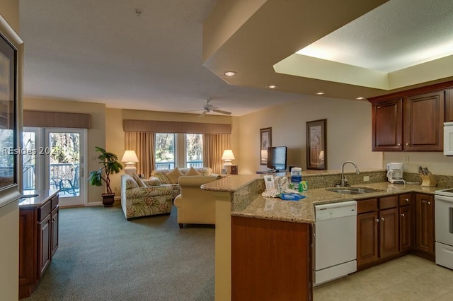 kitchen featuring sink, light colored carpet, light stone counters, kitchen peninsula, and white appliances