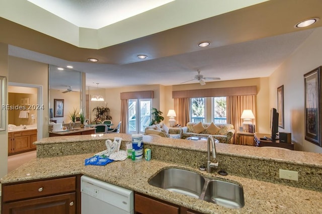 kitchen featuring dishwasher, sink, ceiling fan, and light stone counters