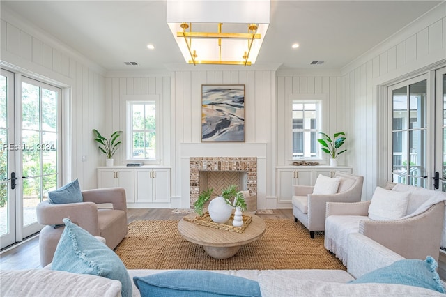 living room with ornamental molding, a brick fireplace, hardwood / wood-style floors, and french doors