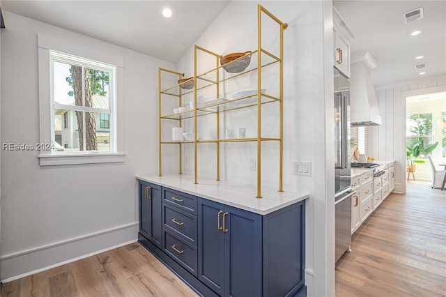 bar featuring blue cabinetry, white cabinets, and light hardwood / wood-style floors