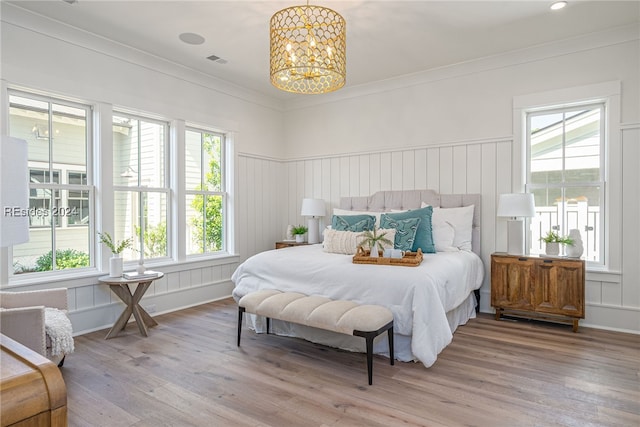 bedroom featuring multiple windows, crown molding, hardwood / wood-style flooring, and a notable chandelier