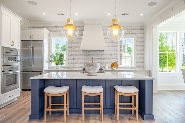 kitchen with premium range hood, decorative light fixtures, white cabinetry, a center island, and stainless steel appliances