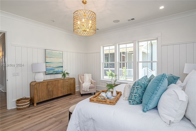 bedroom with a notable chandelier, wood-type flooring, and ornamental molding