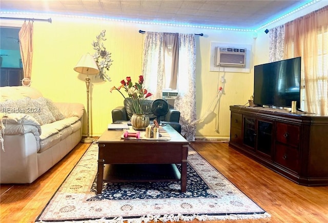 living room featuring ornamental molding, plenty of natural light, a wall unit AC, and light wood-type flooring