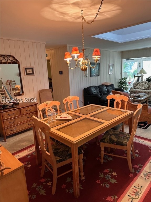 carpeted dining room with a chandelier and wood walls