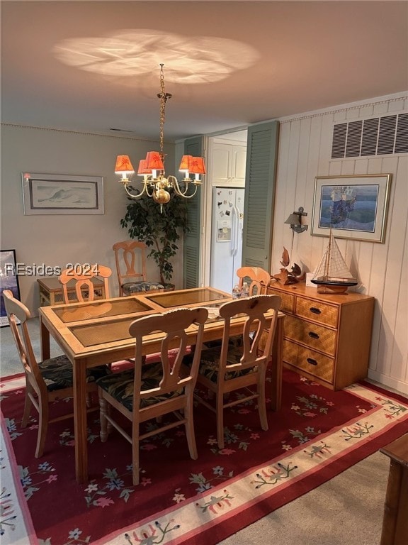 carpeted dining room featuring a notable chandelier and wooden walls