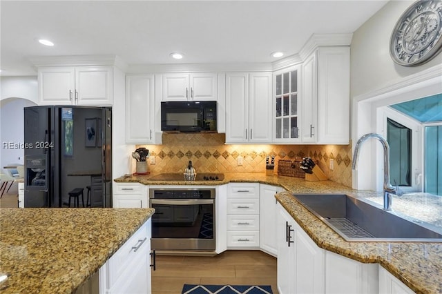 kitchen with stone counters, sink, white cabinets, and black appliances