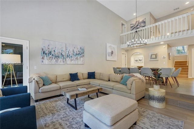 living room featuring hardwood / wood-style flooring, a towering ceiling, and a chandelier