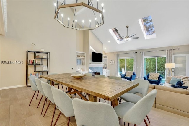 dining area featuring high vaulted ceiling, light hardwood / wood-style floors, and a skylight