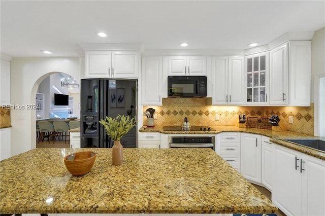 kitchen with white cabinetry, a kitchen island, black appliances, and stone counters