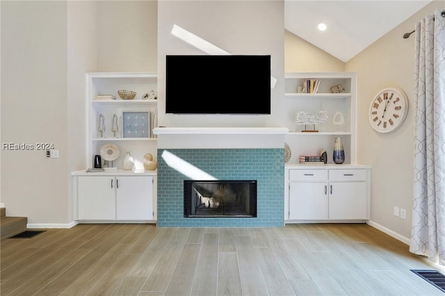 unfurnished living room with lofted ceiling, light hardwood / wood-style flooring, and a tile fireplace