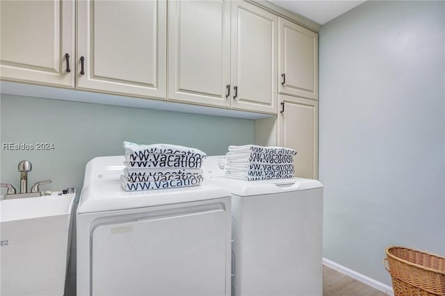 laundry area featuring cabinets, light hardwood / wood-style floors, sink, and washing machine and clothes dryer