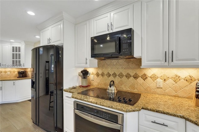 kitchen featuring backsplash, black appliances, dark stone counters, and white cabinets