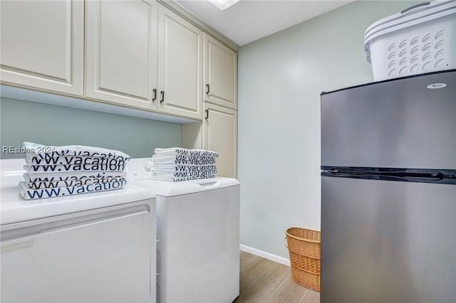 laundry area featuring cabinets, washer and clothes dryer, and light hardwood / wood-style flooring