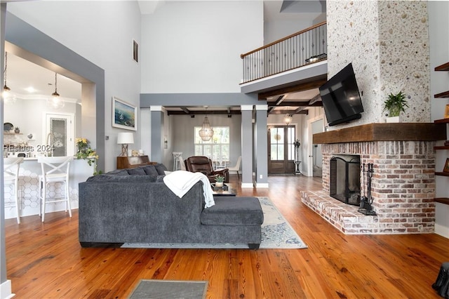 living room with a towering ceiling, wood-type flooring, and a fireplace