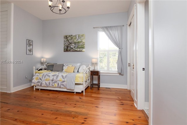 bedroom with wood-type flooring and an inviting chandelier