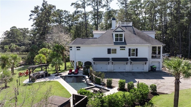 rear view of property with a garage, a yard, and a swimming pool