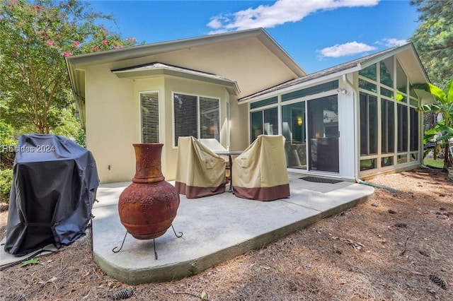 back of house featuring a patio, a fire pit, and a sunroom