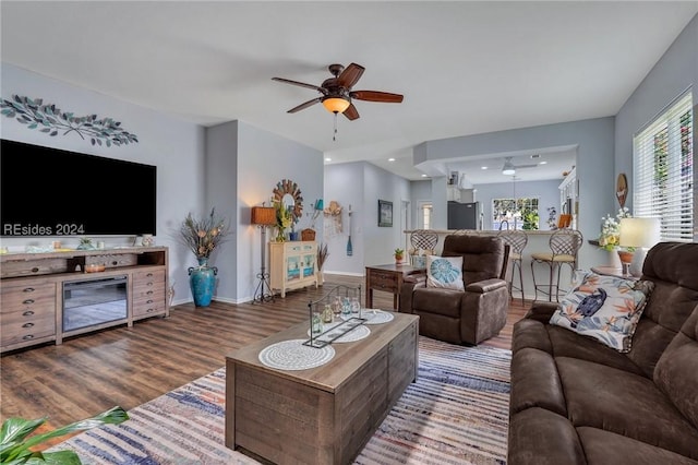 living room featuring dark wood-type flooring and ceiling fan