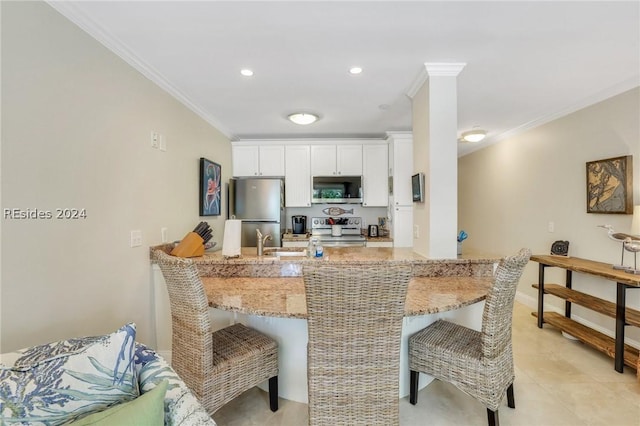 kitchen featuring a kitchen bar, white cabinetry, ornamental molding, appliances with stainless steel finishes, and kitchen peninsula