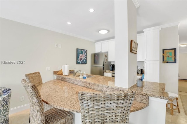 kitchen featuring sink, white cabinetry, crown molding, stainless steel refrigerator, and kitchen peninsula