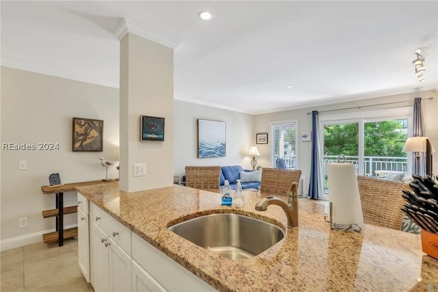 kitchen featuring sink, light stone counters, white cabinetry, crown molding, and light tile patterned floors