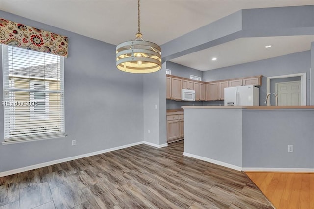 kitchen with light brown cabinetry, decorative light fixtures, hardwood / wood-style flooring, a notable chandelier, and white appliances