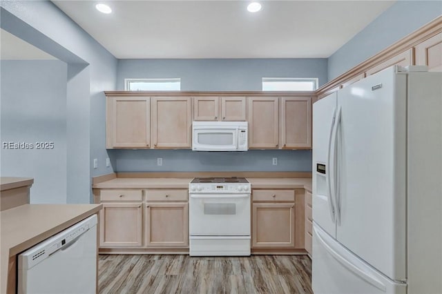 kitchen with light brown cabinets, white appliances, and light hardwood / wood-style flooring