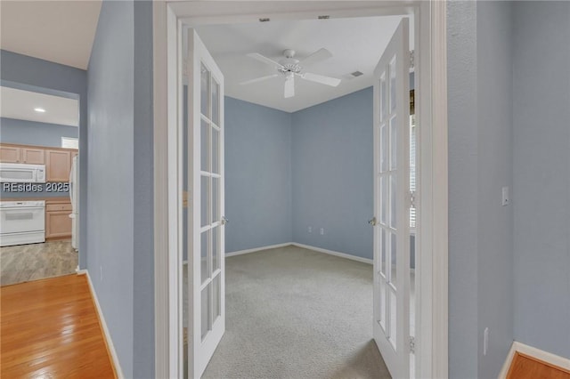 hallway featuring light carpet and french doors