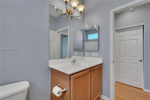 bathroom with vanity, a notable chandelier, hardwood / wood-style flooring, and toilet